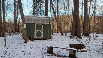 A cabin with a snow-covered ground, surrounded by trees.
