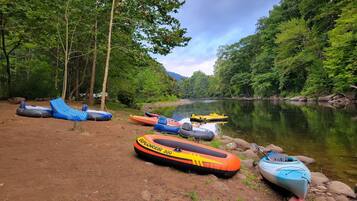 A riverbank with several inflatable rafts and a kayak.
