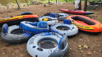A collection of inflatable rafts on a dirt ground near a body of water.