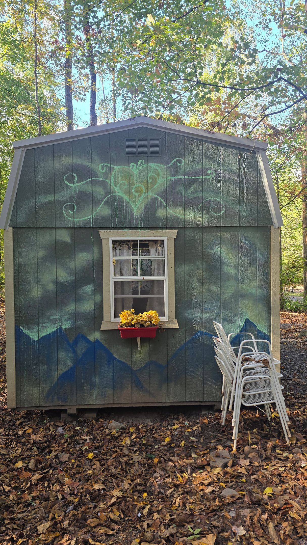 Ein kleines Holz-Shed mit einem Fenster und einem roten Blumentopf.