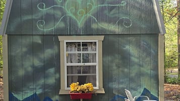 Ein kleines Holz-Shed mit einem Fenster und einem roten Blumentopf.