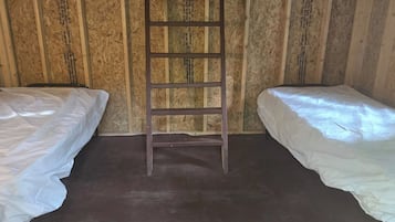 A room with two beds, a ladder, and wooden panel walls.