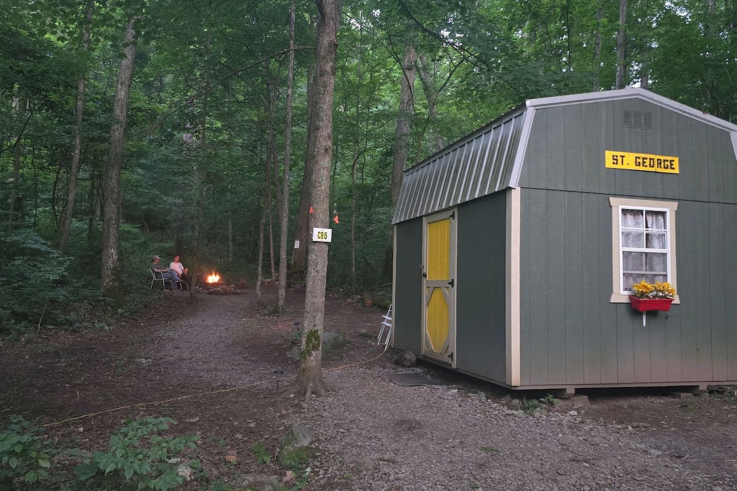 Une petite cabane en bois portant l’inscription « St. George », avec une porte jaune, une fenêtre agrémentée d’une jardinière et un panneau indiquant « CB5 ».