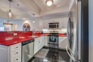 A modern kitchen with white cabinets, stainless steel appliances, and a red countertop. - Cozy 2-bedroom Trackside Retreat condo in fantastic Bristol (Bristol)
