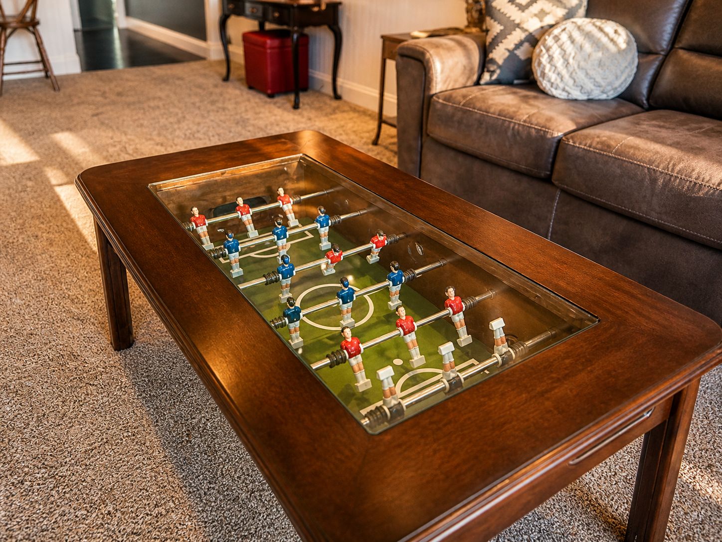 A wooden coffee table with a foosball table on top.