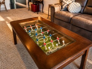 A wooden coffee table with a foosball table on top.