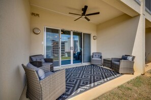 A covered patio area with wicker furniture, a ceiling fan, and a patterned rug.
