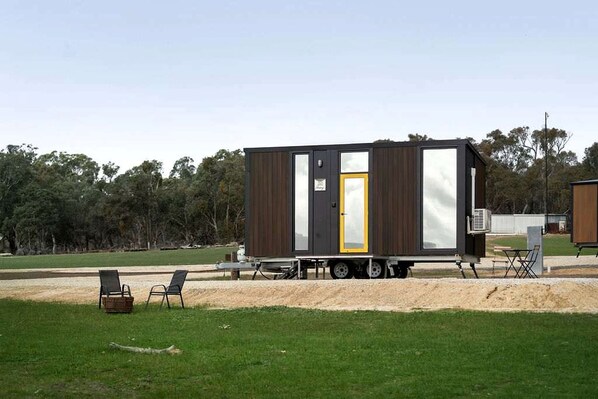 A mobile home with a sliding door, a small porch area, and a trailer setup.