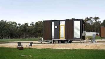 A mobile home with a sliding door, a small porch area, and a trailer setup.