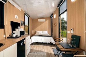 Habitación compacta con cama, un escritorio pequeño, microondas y vistas al exterior.