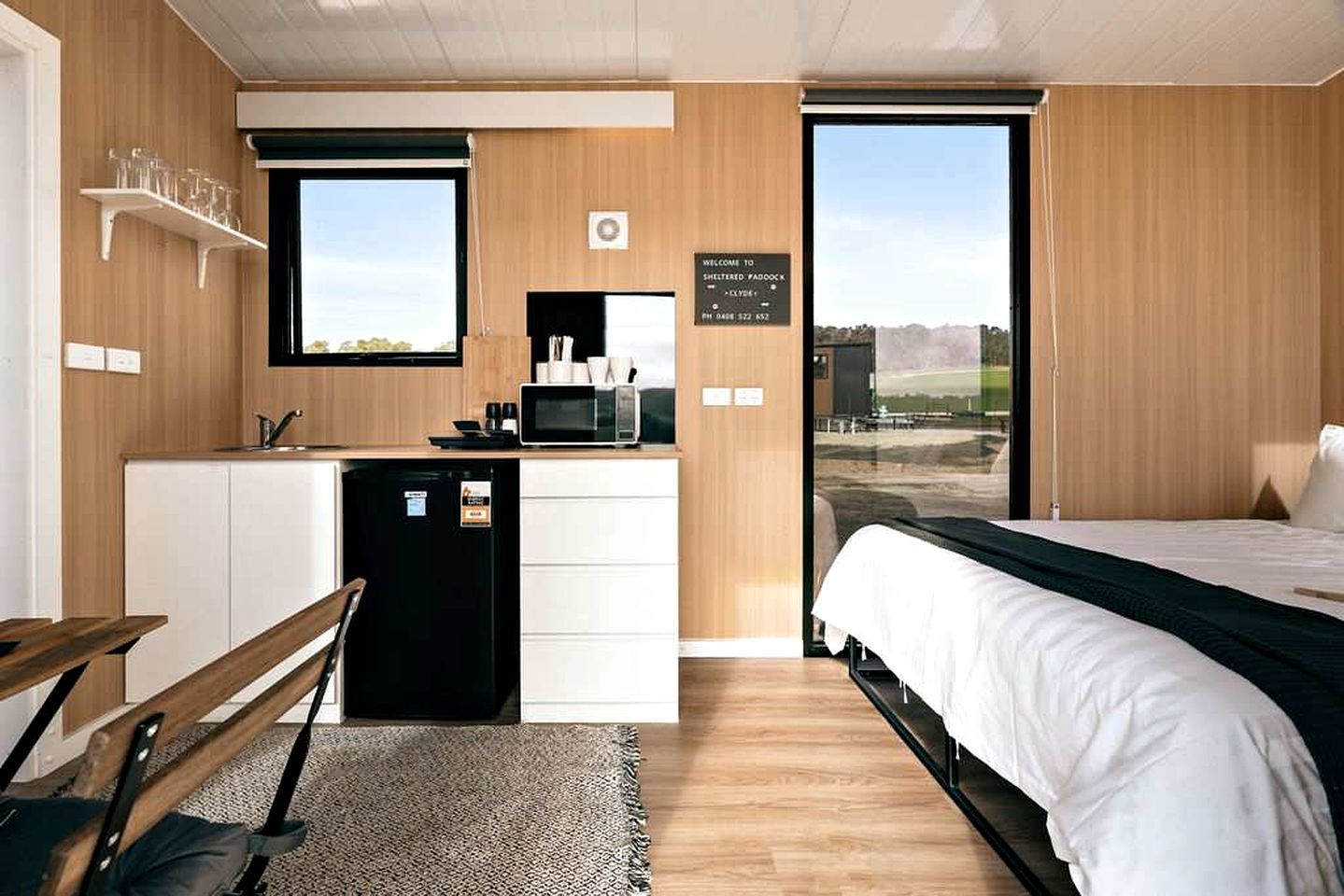 A compact room with a bed, a small kitchenette, a window, and a view of the outdoors.
