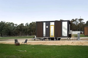 A mobile home with a sliding door, a small porch area, and a trailer setup.