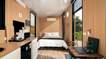 Habitación compacta con cama, un escritorio pequeño, microondas y vistas al exterior.