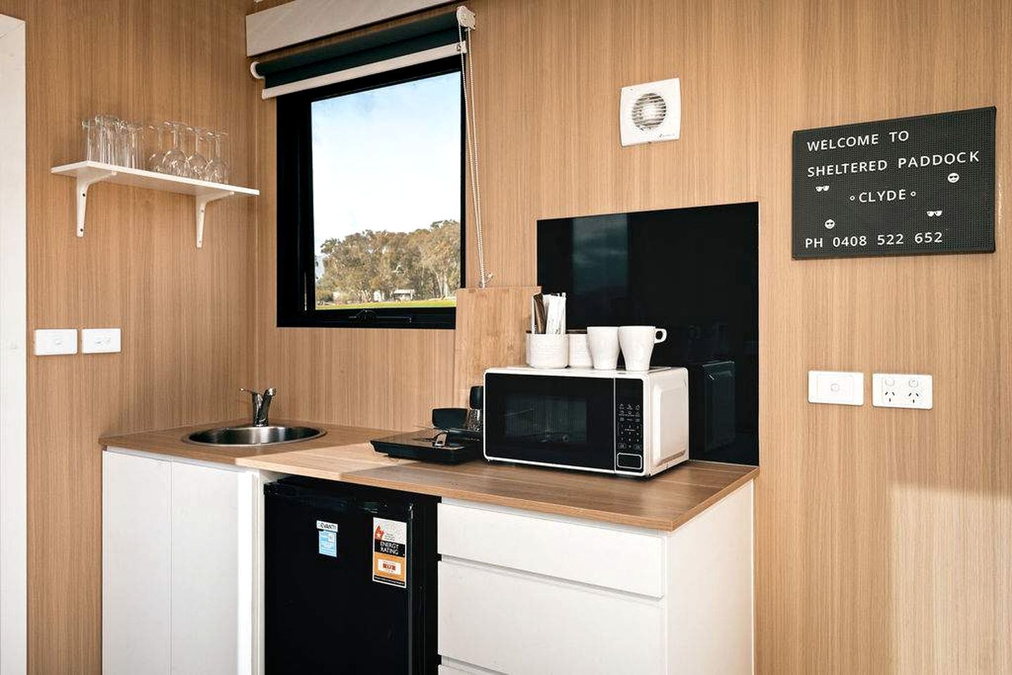 Una cocina moderna con microondas integrado, una ventana y un cartel de bienvenida.