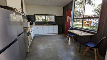 A compact kitchen with a refrigerator, cabinets, a sink, and a window overlooking a yard.