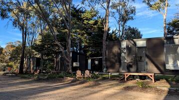 A campsite with a wooden structure, two chairs, and a bench.