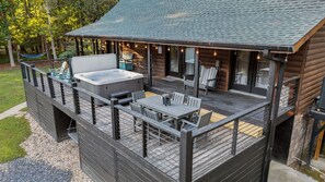 Eine Holzterrasse mit Sitzgelegenheiten im Freien, einem Whirlpool und Lichterketten.