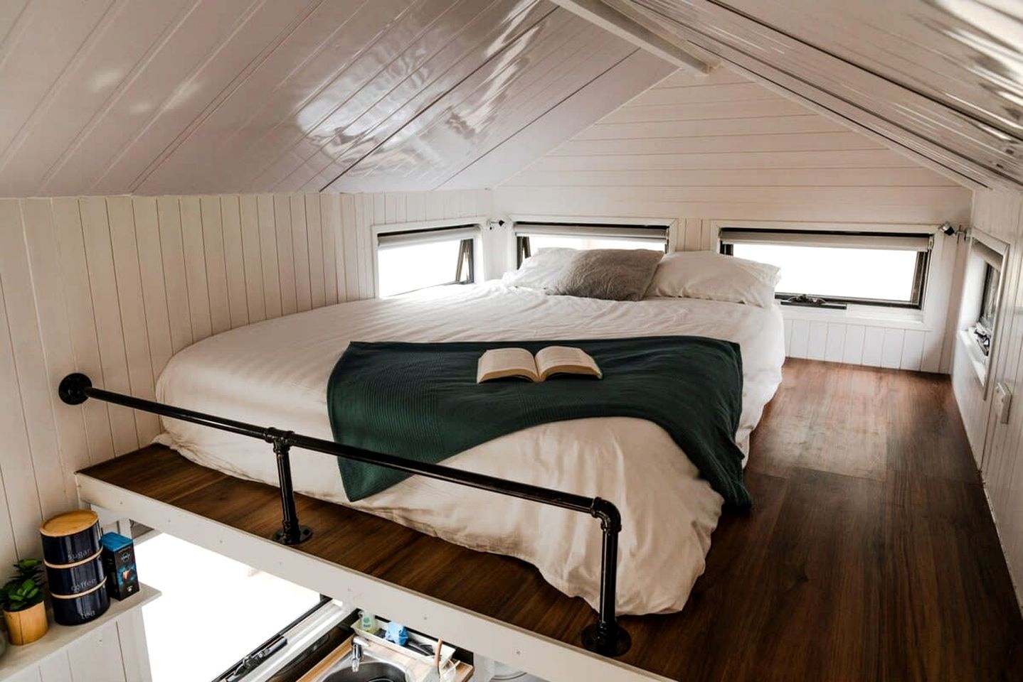 A bedroom with a bunk bed, a window, and a small kitchenette area.