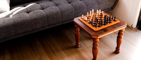 A chessboard on a wooden table with a dark sofa in the background.