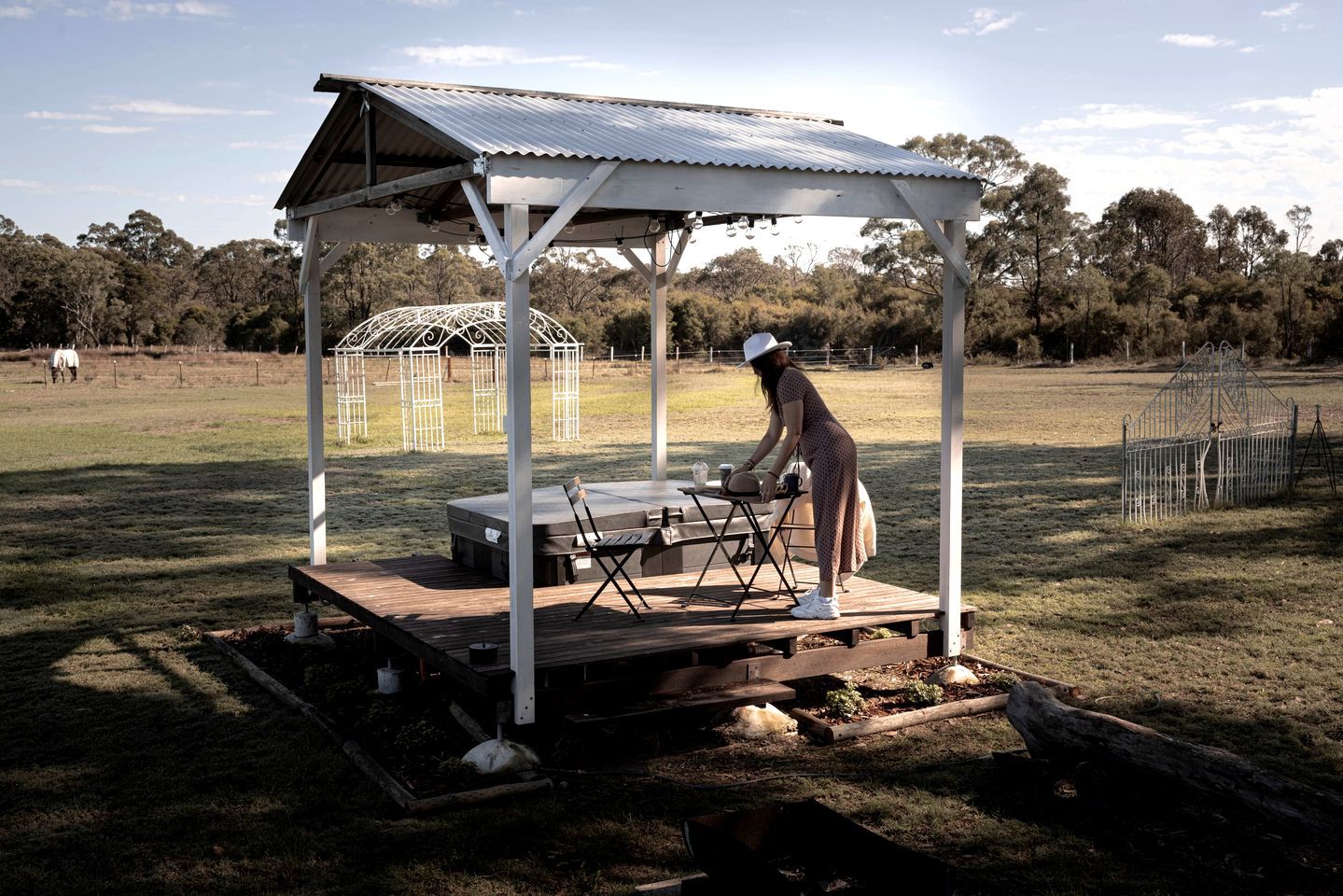 Ein Kiosk mit Metallveranda und Bühne, umgeben von einer Wiese und Bäumen.