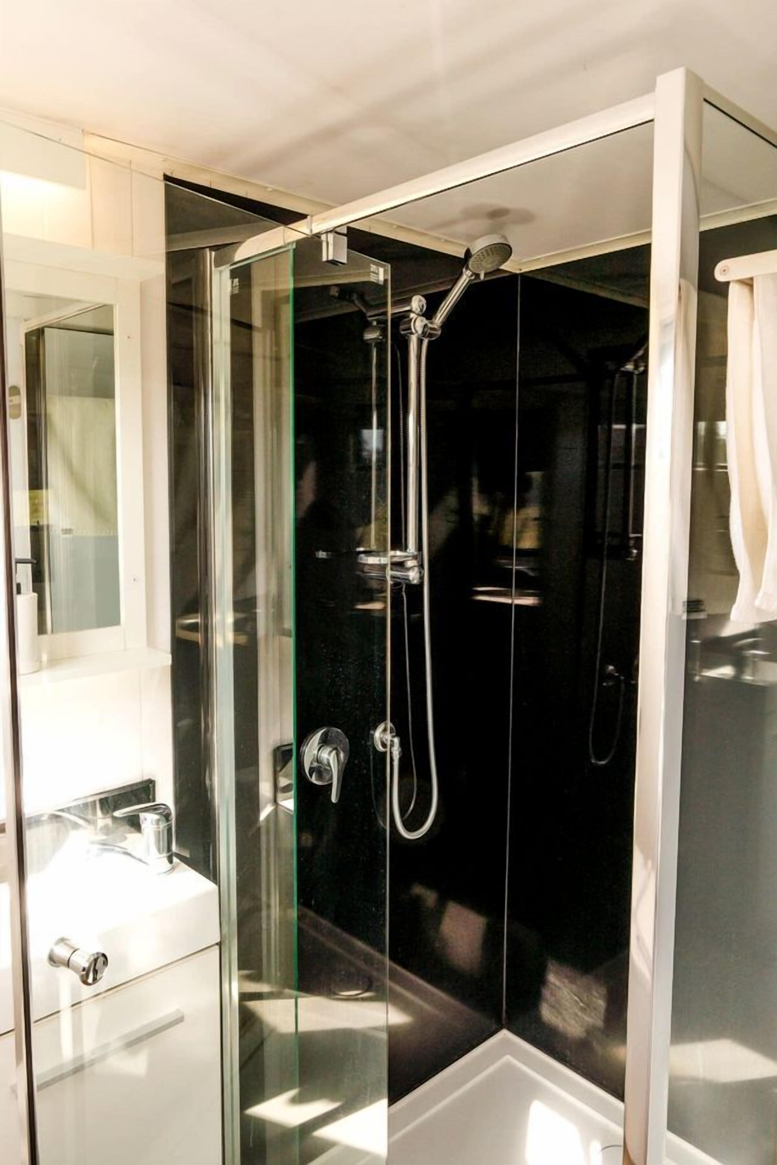 Une salle de bain moderne avec une douche à parois de verre, un lavabo blanc et un miroir.