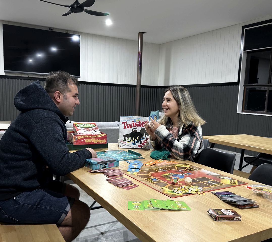 Dos personas jugando juegos de mesa en una mesa con varias cajas de juegos y cartas.
