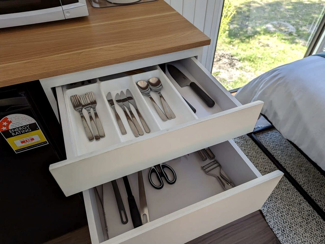 A drawer with utensils and a pair of scissors.