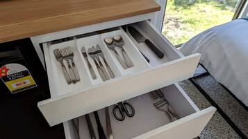 A drawer with utensils and a pair of scissors.