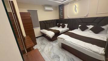 A hotel room with two beds, a ceiling fan, an air conditioning unit, and a decorative wall panel.