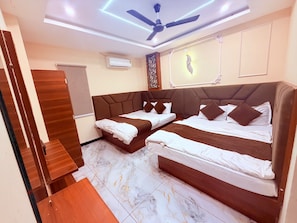 Habitación de hotel con dos camas, ventilador de techo, aire acondicionado y un adorno en la pared.