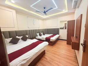 Habitación de hotel con dos camas, ventilador de techo y piso de madera.