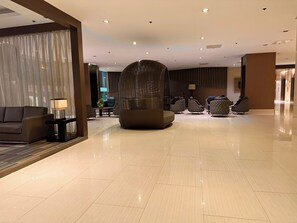 A modern lobby with a sofa, a unique sculptural seating area, and a clean, tiled floor. - Luxury Seaside Sunset View Mall of Asia with Free Parking (Pasay City)