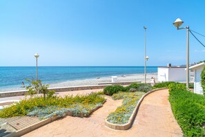 A coastal walkway with a view of the beach, street lamps, and a building with a white facade. - Villa in Nerja Near Burriana Beach (Nerja)