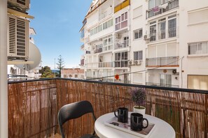 Ein Balkon mit einem Stuhl, einem Tisch und einer Ablage mit zwei schwarzen Tassen.