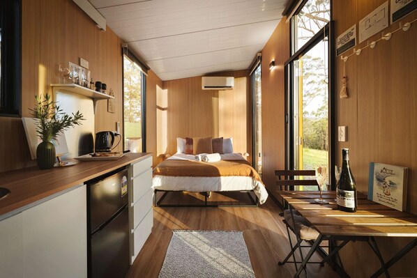 Un dormitorio moderno con cama, mesita de noche y vistas al exterior.