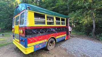 Ein farbenfroher Bus, der an einem Schotterweg inmitten von Bäumen parkt.