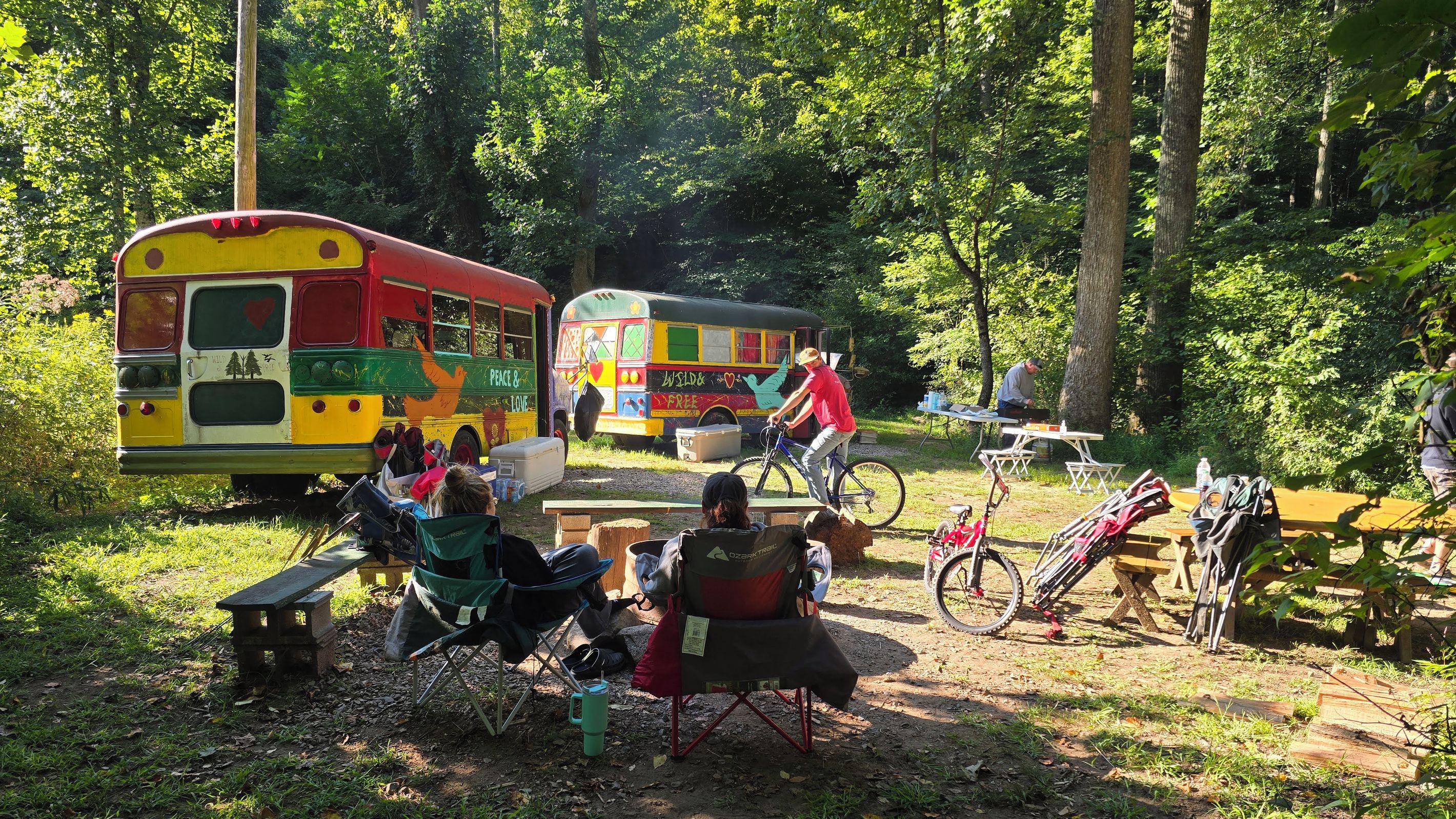 A campsite with colorful buses, a picnic table, and bicycles.