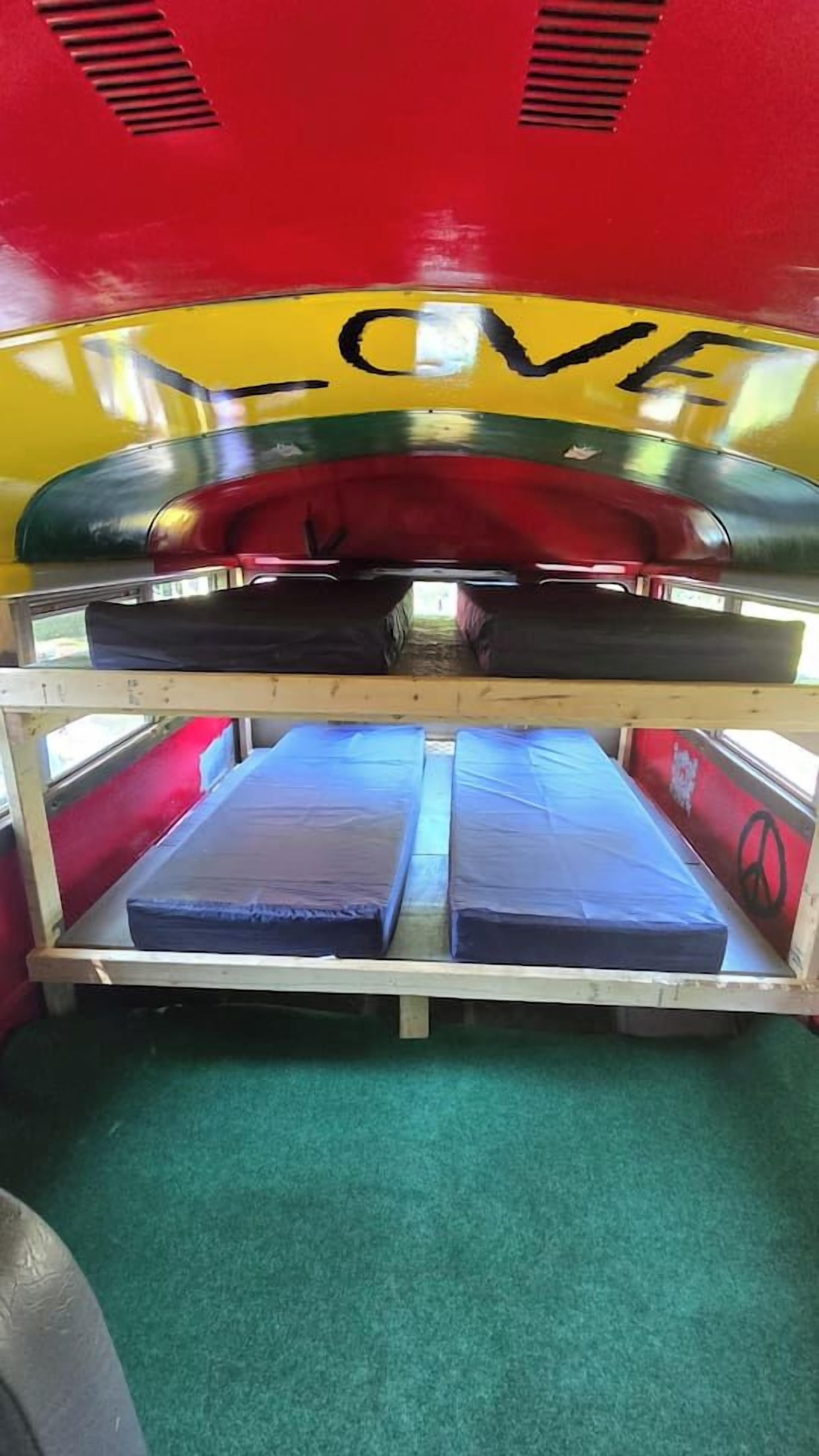 A bunk bed with a mattress on the lower bunk and a red and yellow wall with the word 'LOVE' written on it.