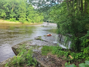 A river with a small boat, a waterfall, and dense greenery.