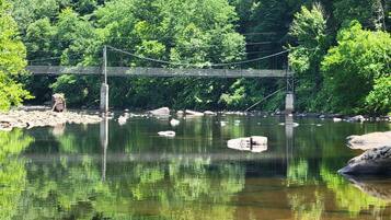 Eine Hängebrücke über einem ruhigen Fluss, gesäumt von üppiger Vegetation.