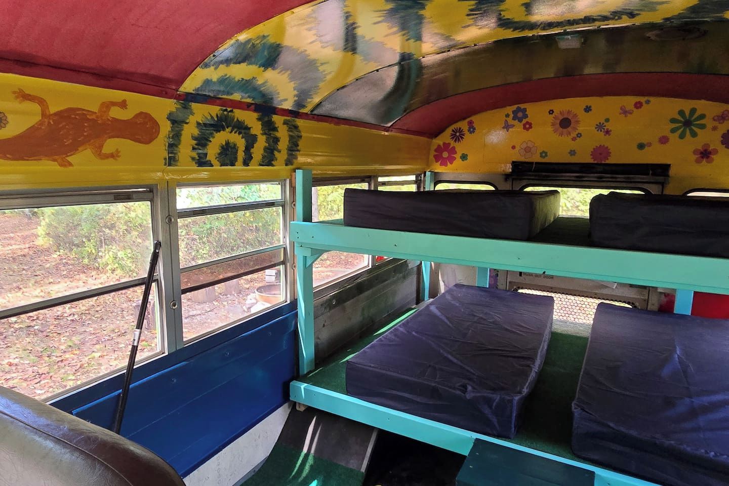 L'intérieur d'un autobus, avec des couchettes, une fenêtre et une fresque murale.