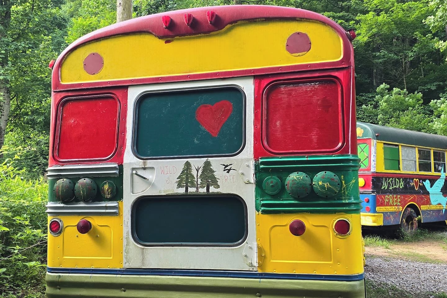 Un autobús colorido con un corazón y árboles pintados en la parte trasera.