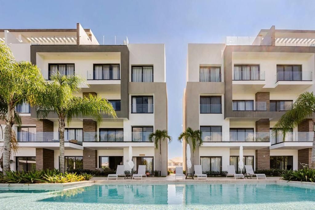 Un hôtel moderne doté d’une piscine, de nombreux balcons et offrant une vue sur un ciel dégagé.