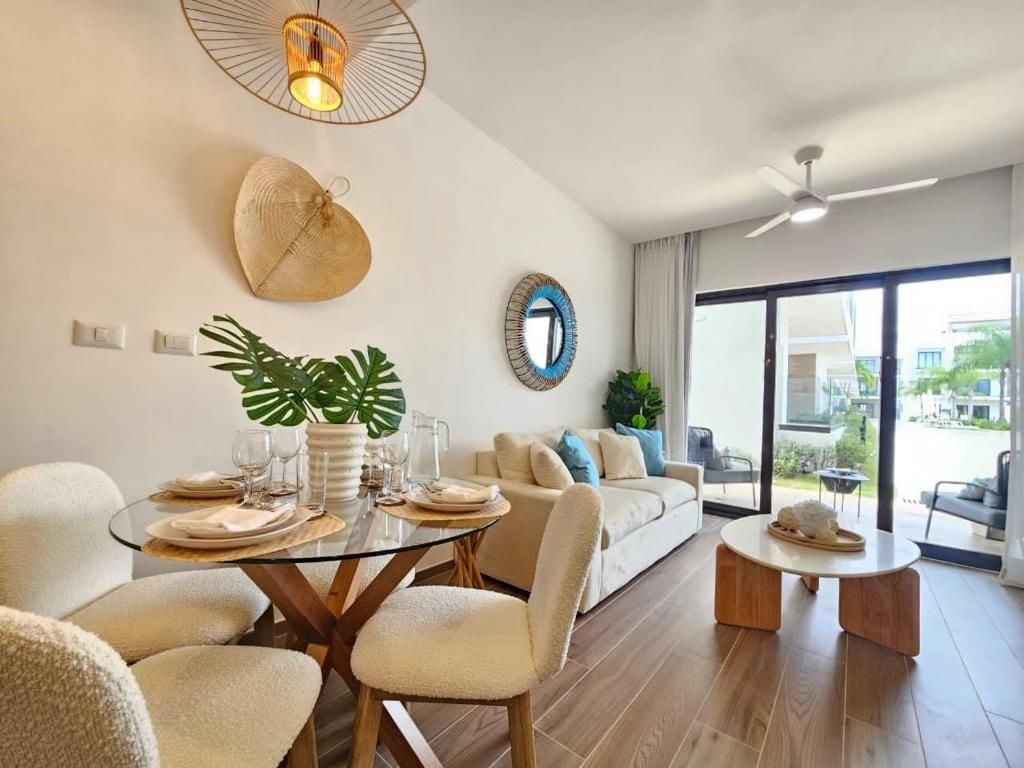 A modern living room with a glass dining table, a sofa, and a coffee table.