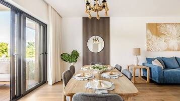 A modern dining area with a wooden table set for four, a large mirror, and a blue sofa in the background.