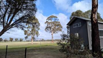 A fenced property with a building, trees, and a clear sky.