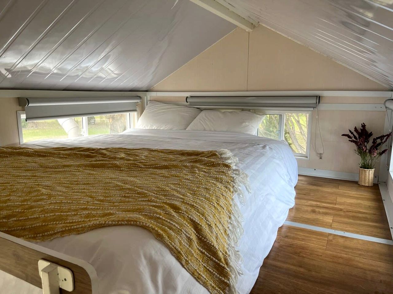 Ein Schlafzimmer mit Bett, Fenster und einer Topfpflanze.