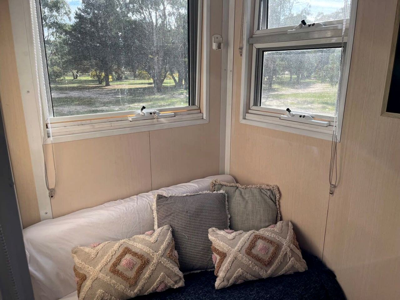 A room with a bed, two windows, and a view of trees.