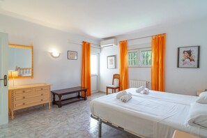 A hotel room with a bed, a bedside table, a dresser, a chair, and a window with curtains. - Villa in Nerja With Pool Near Burriana Beach (Nerja)