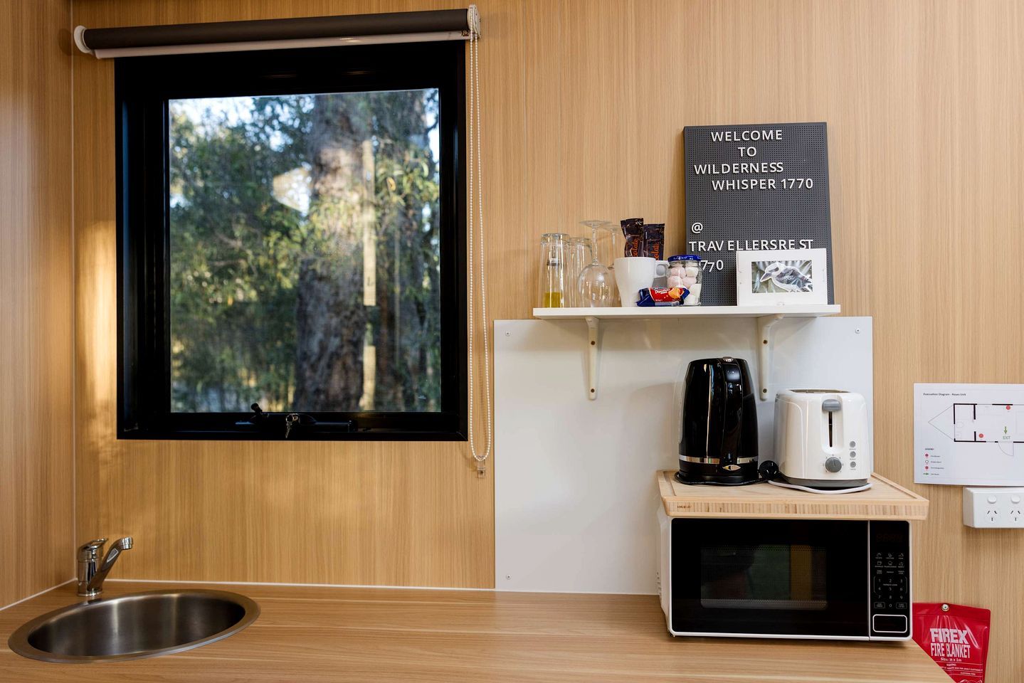 A modern kitchen with a window, a welcome sign, a coffee maker, a toaster, and a microwave.